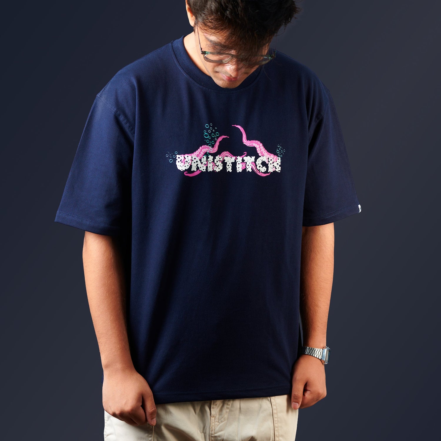 Person wearing a navy blue t-shirt with a logo and text on a dark background